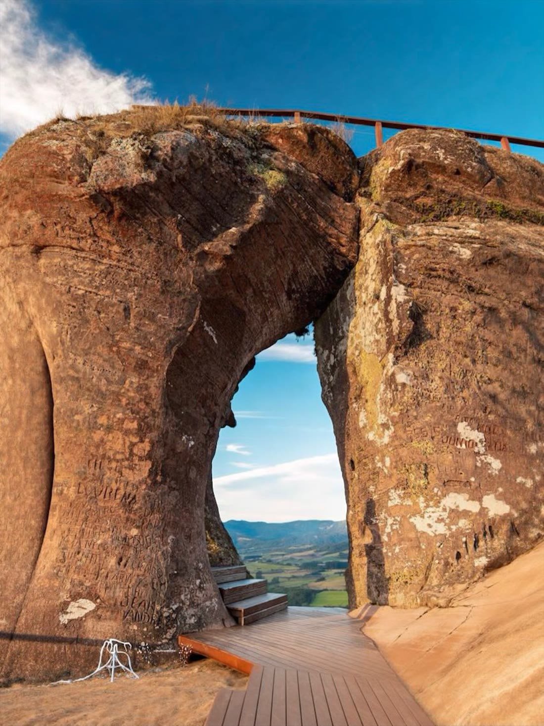 O arco de arenito visto do deck de madeira, com o vale enquadrado pela janela na rocha