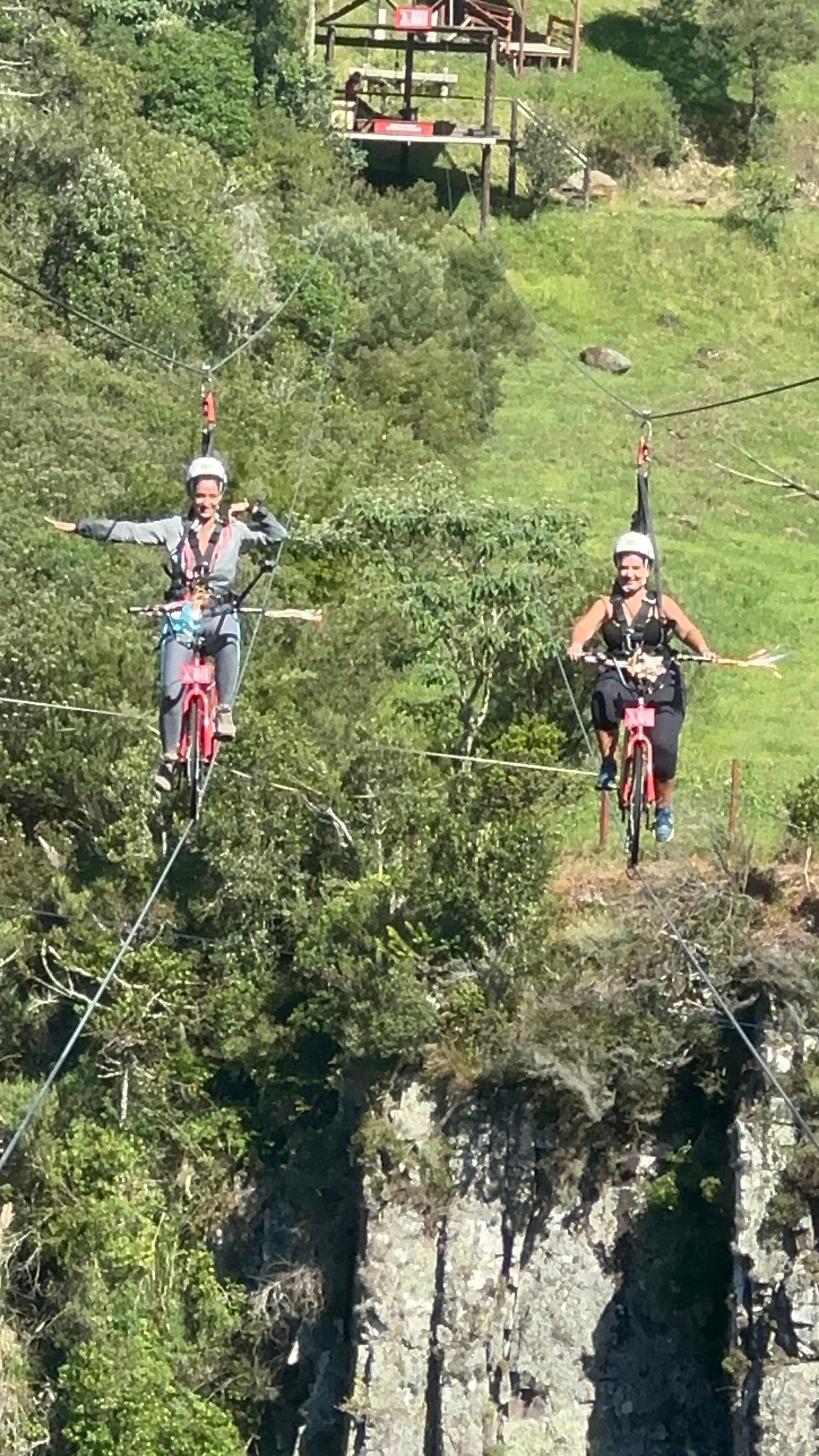 Duas pessoas atravessando o canion nas bicicletas suspensas da Tirolesa de Bike