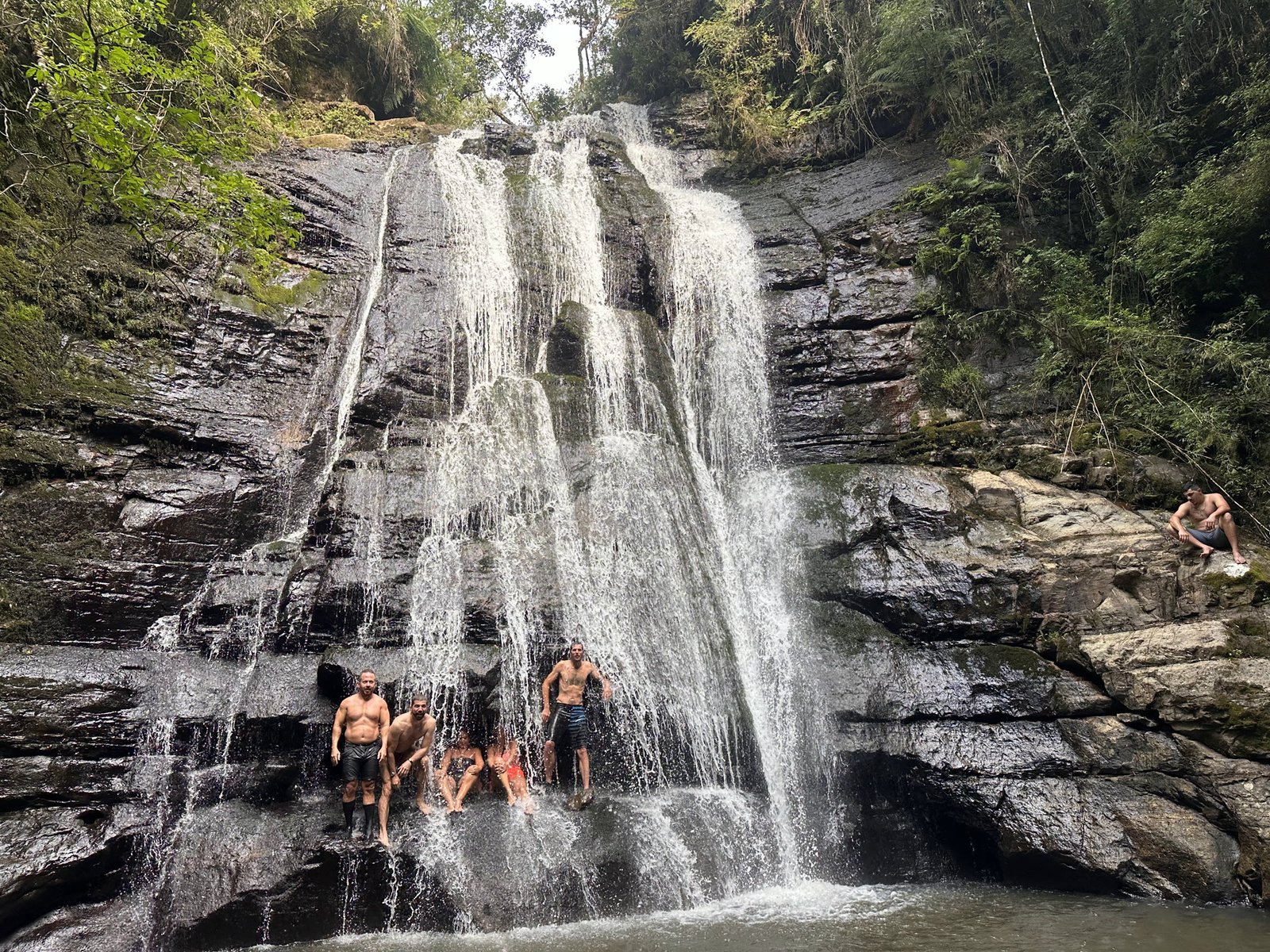 A queda alta do Sitio Sete Quedas, com pessoas na base dando a escala